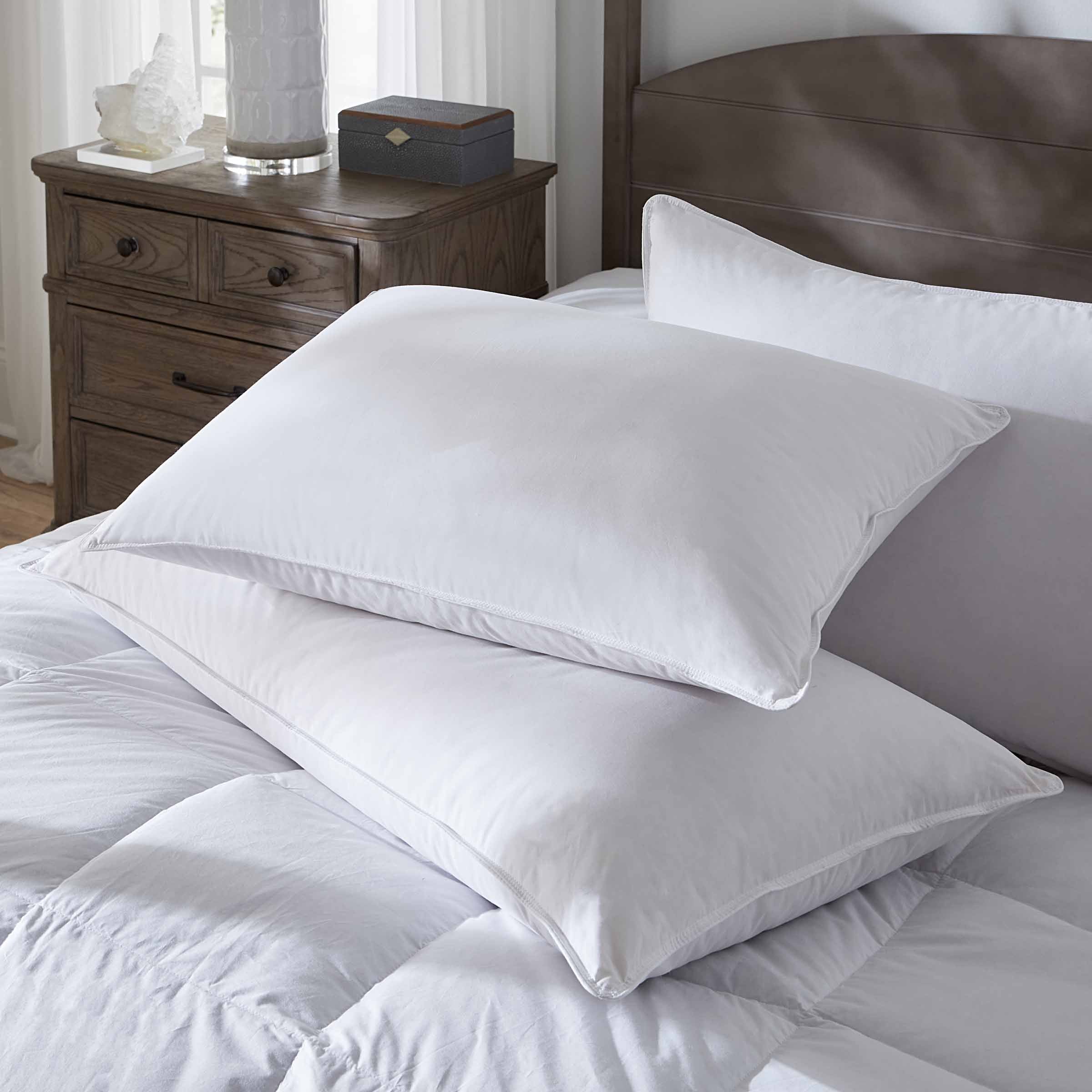 White pillows on a bed with a wooden nightstand in the background