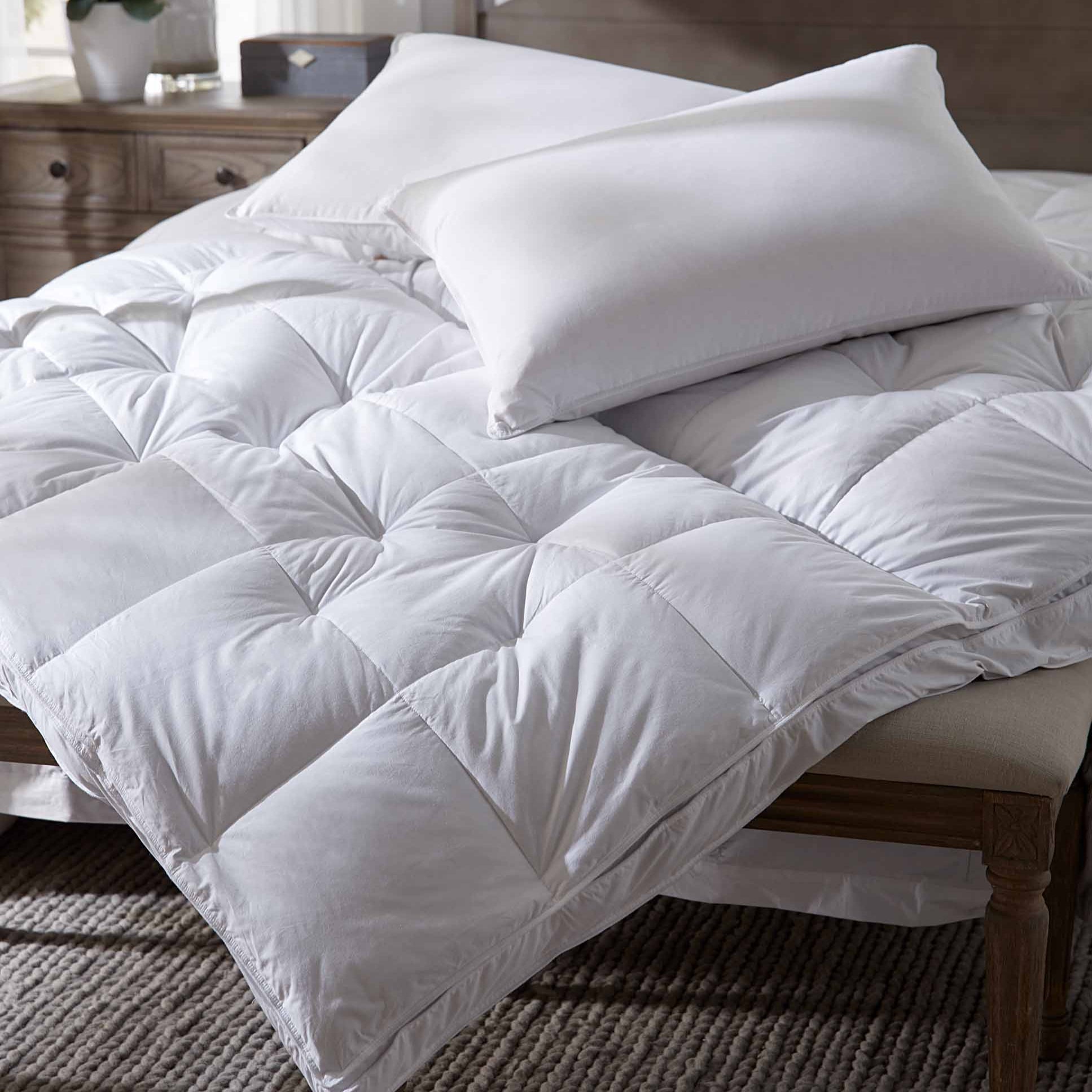 White comforter and pillows on a bed in a bedroom setting