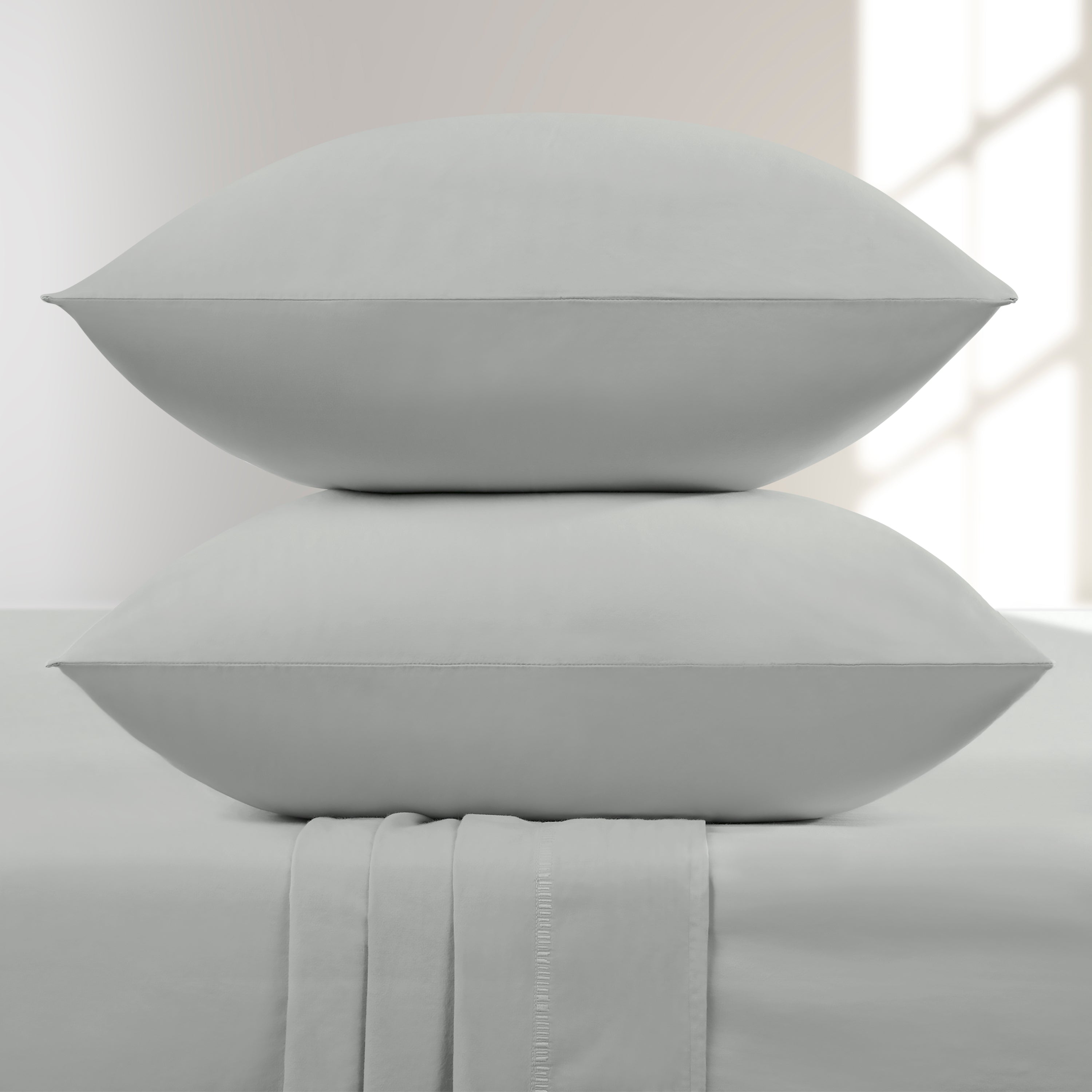 Oystershell pillowcases on a bed with a neutral background