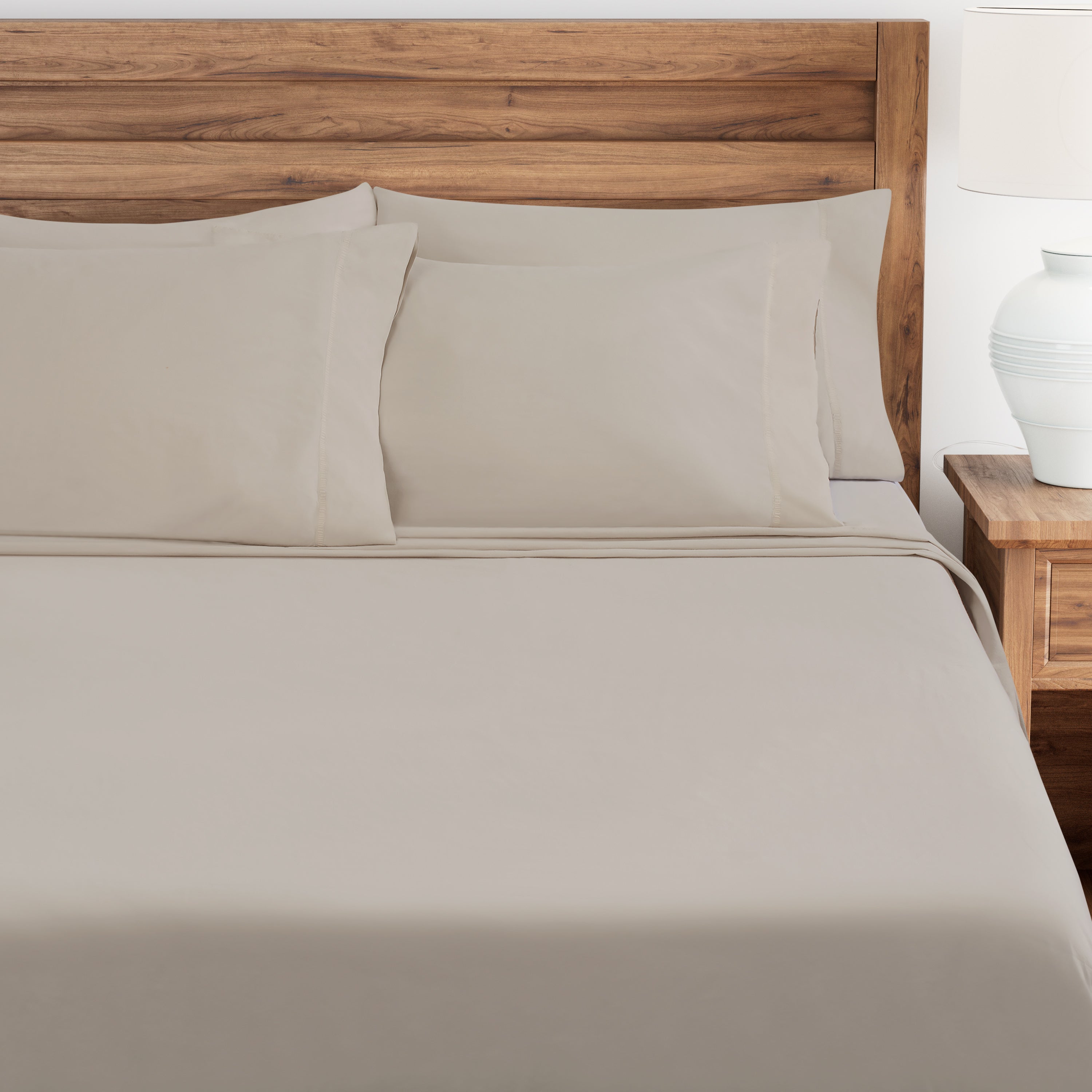 Pumice bed sheets and pillows on a wooden bed with a nightstand in the background.