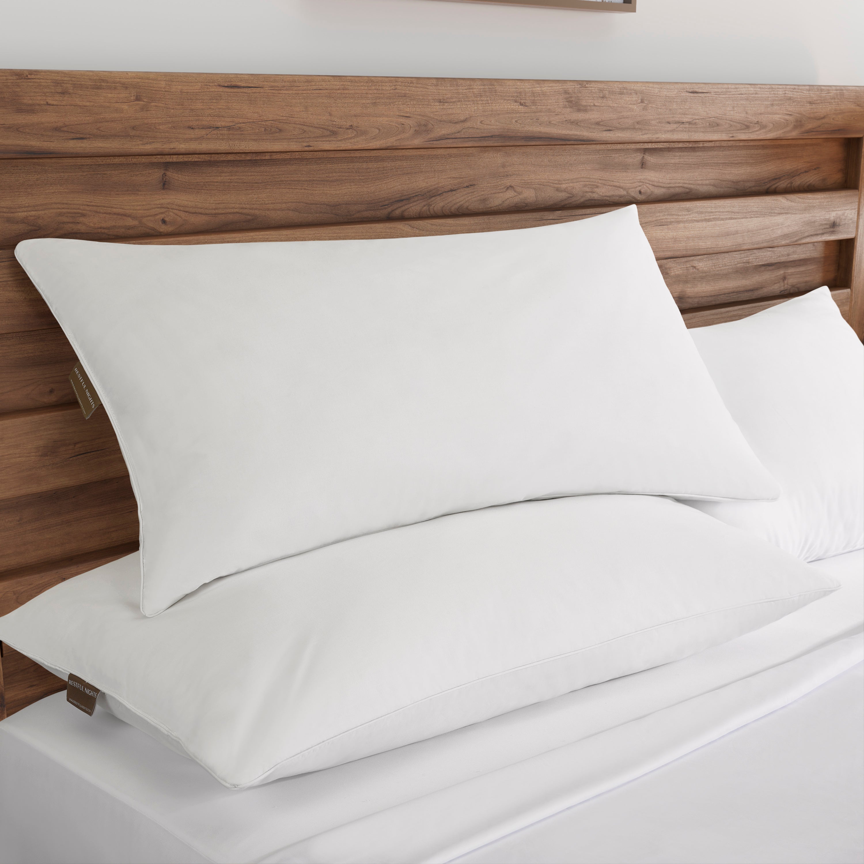 White pillows on a bed with a wooden headboard