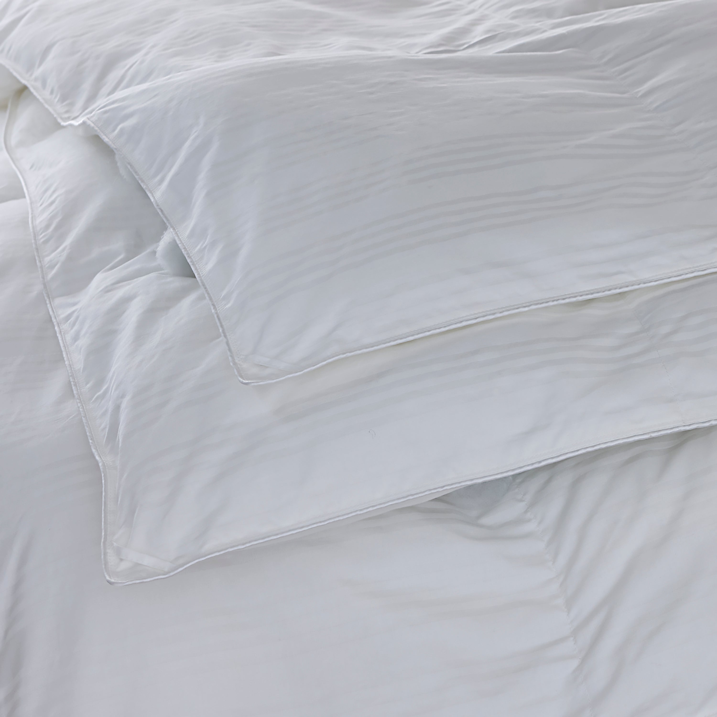 White comforter on a bed with a subtle pattern