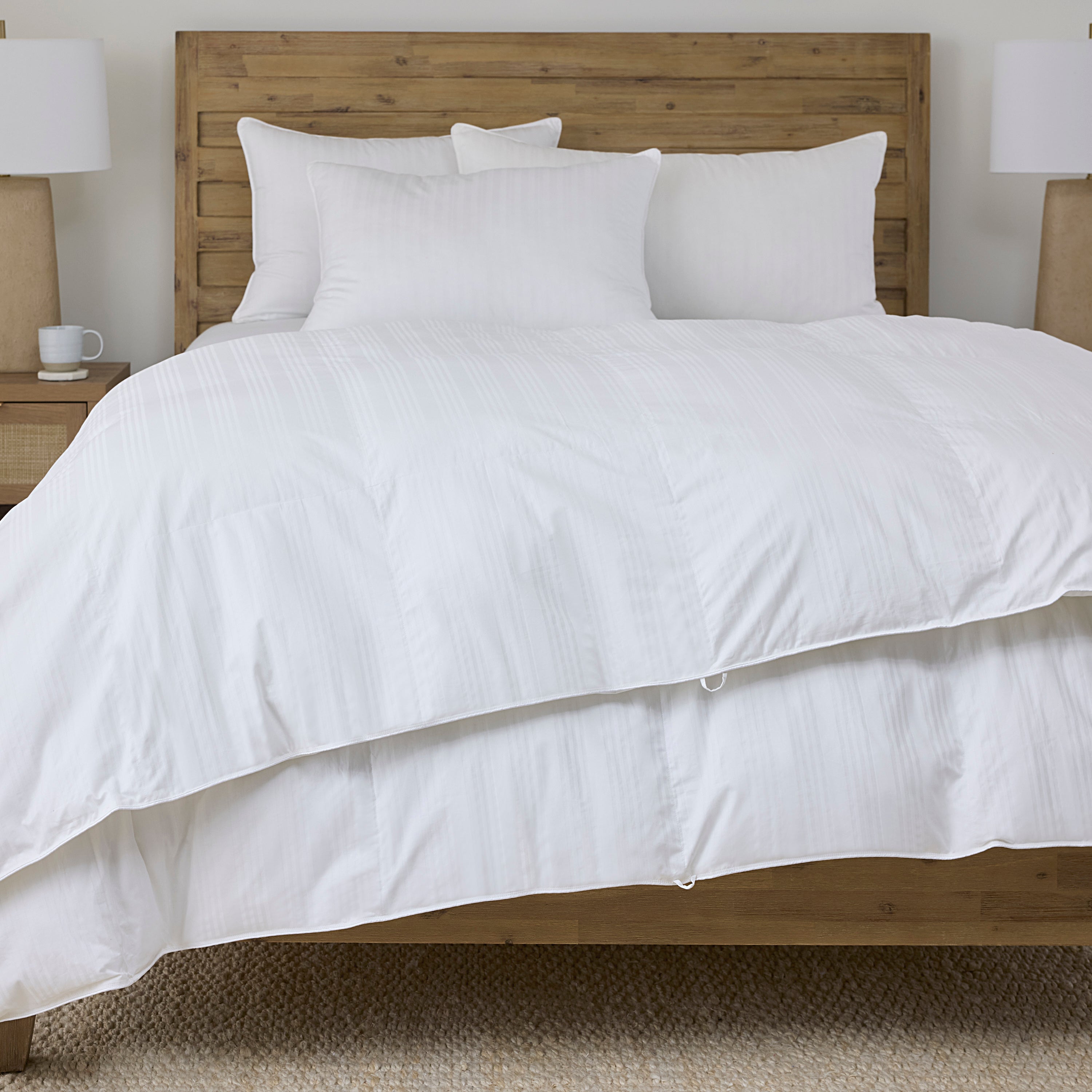 White comforter on a bed with wooden headboard and nightstands.