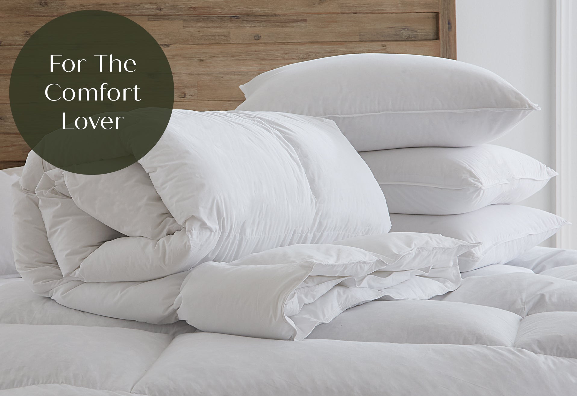 White comforter and pillows on a bed with 'For The Comfort Lover'