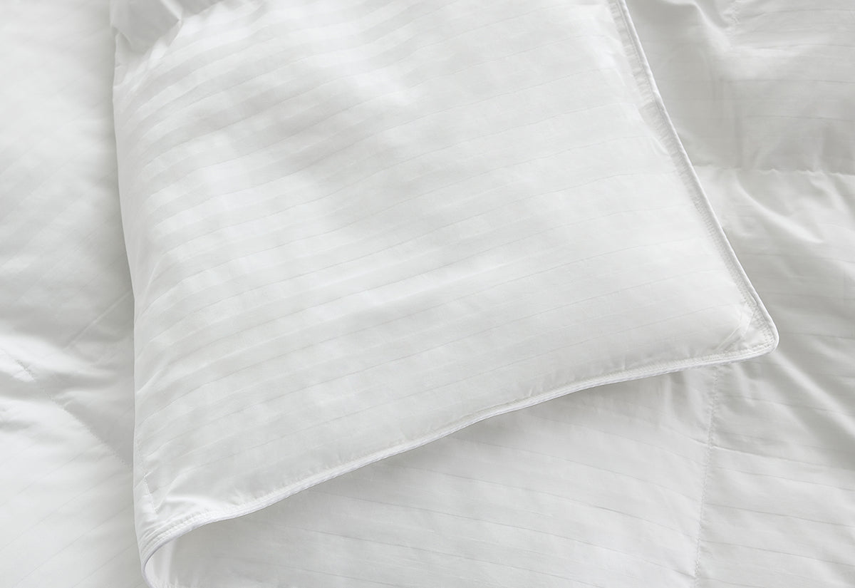 A close-up of a white comforter folded.